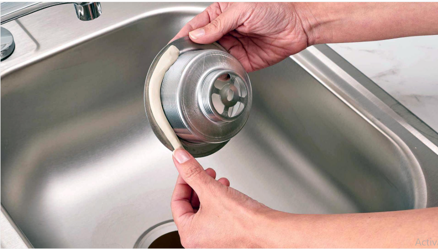 Applying a suitable sealing material around a kitchen sink drain flange to create a watertight seal.