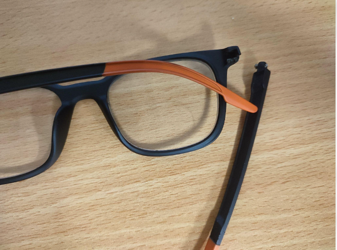 Broken eyeglasses frame with a clearly visible crack at the bridge, illustrating a common glasses repair problem.