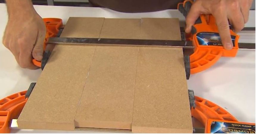 Two MDF boards secured tightly together with woodworking clamps while the wood glue cures.