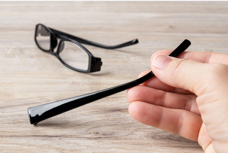 Inspecting a broken plastic eyeglasses frame to identify the damaged area before repair.