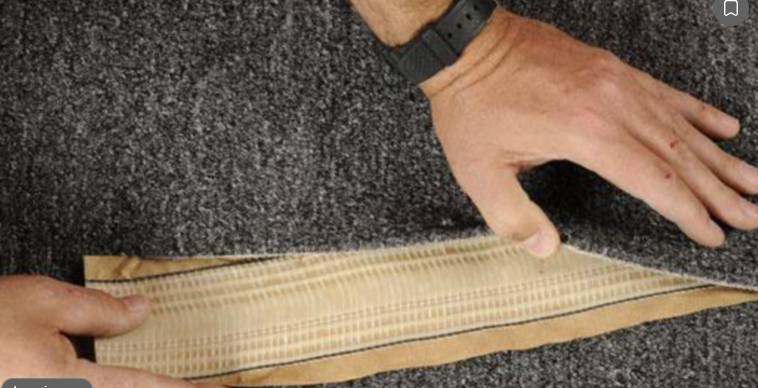 Carpet edges folded back carefully to position heat-activated seaming tape underneath the joint before bonding.