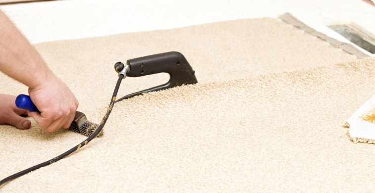 Carpet seam being gently pressed with a seam roller to bond the carpet backing to the adhesive tape and blend the pile.