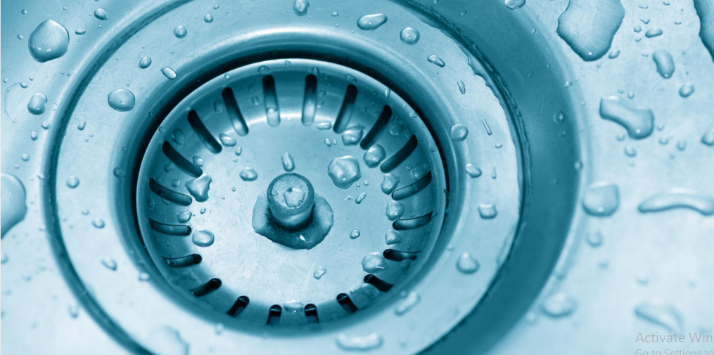 Stainless steel kitchen sink with small amounts of water on its surface.